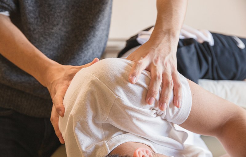 A picture of a massage therapist working on the shoulder and back of a client
