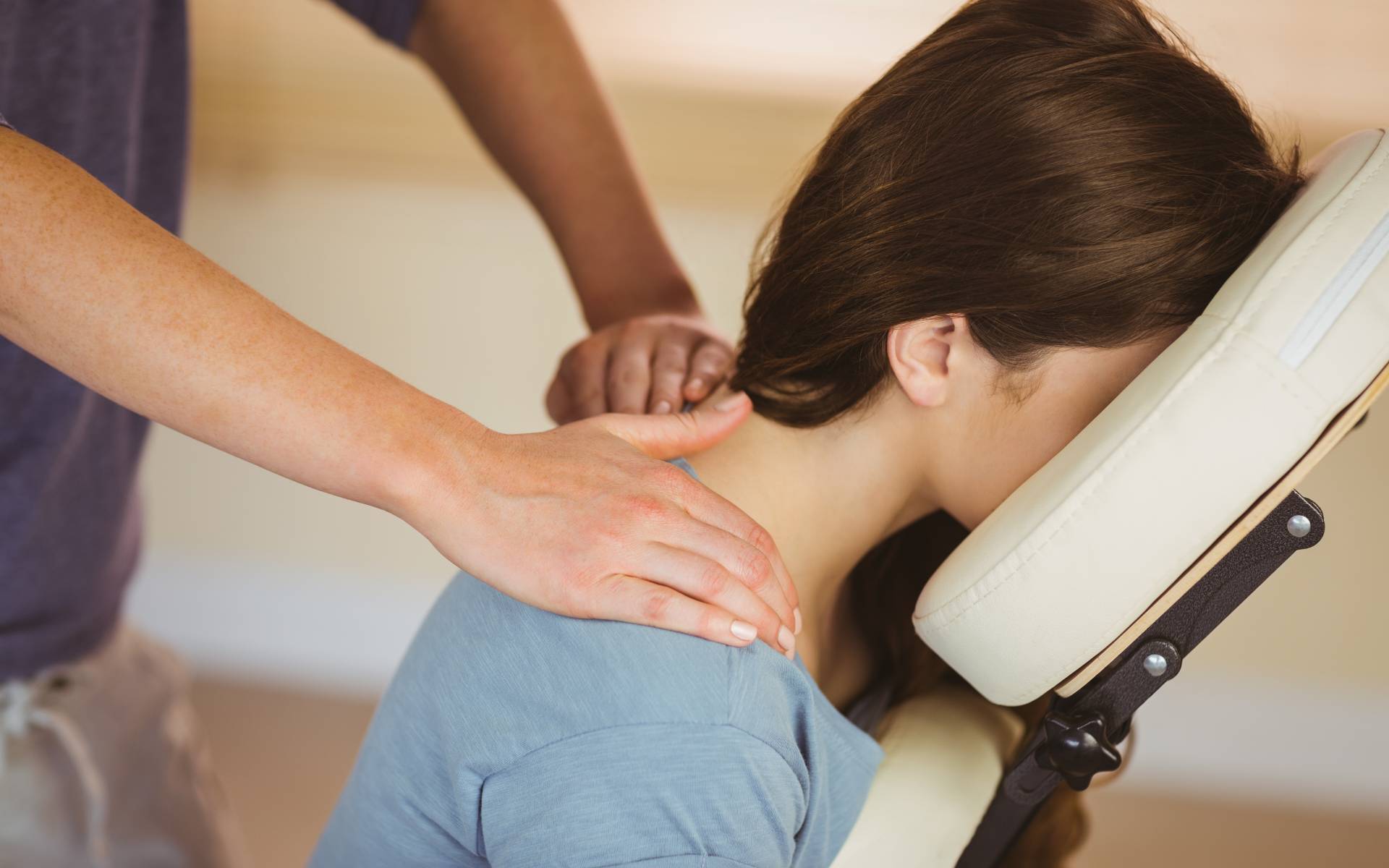 An image of a woman who is sitting down while getting her back massaged.