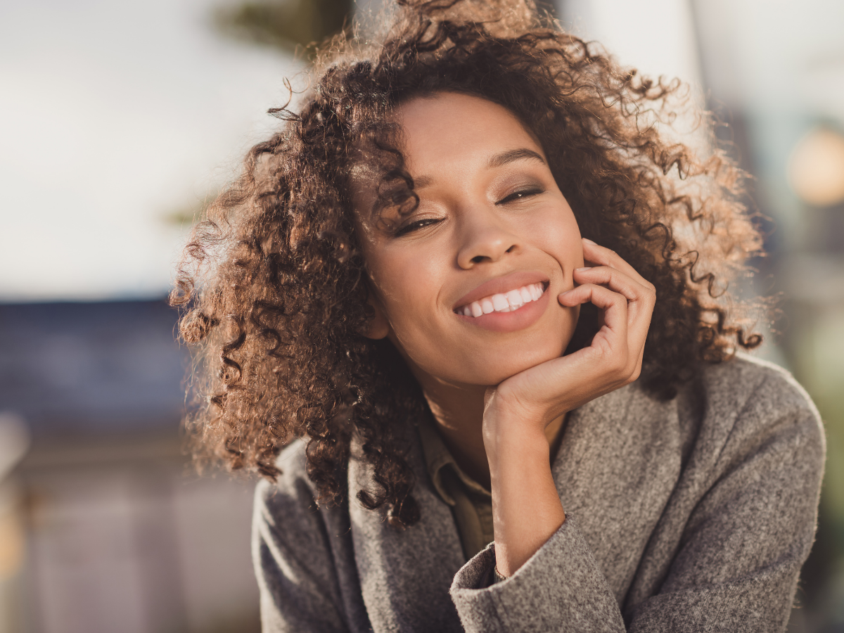 An image of a lady with curly hair smiling.