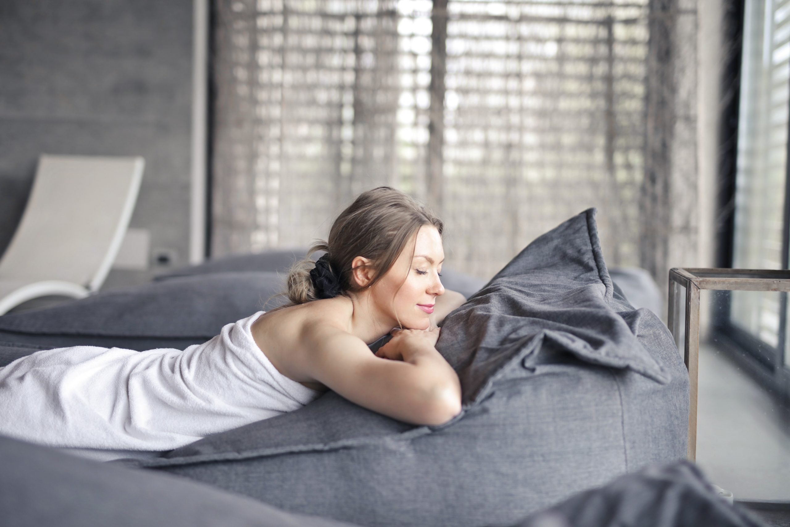 An image of a lady relaxing on a grey bed.