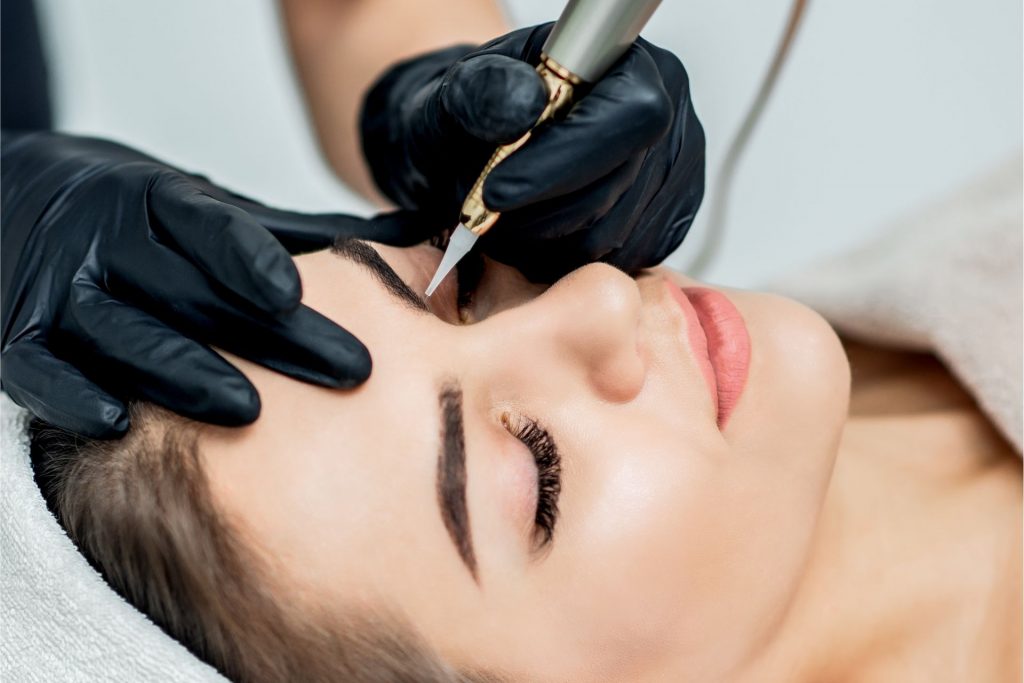 Woman laying down while professional removes her eyebrow tattoo