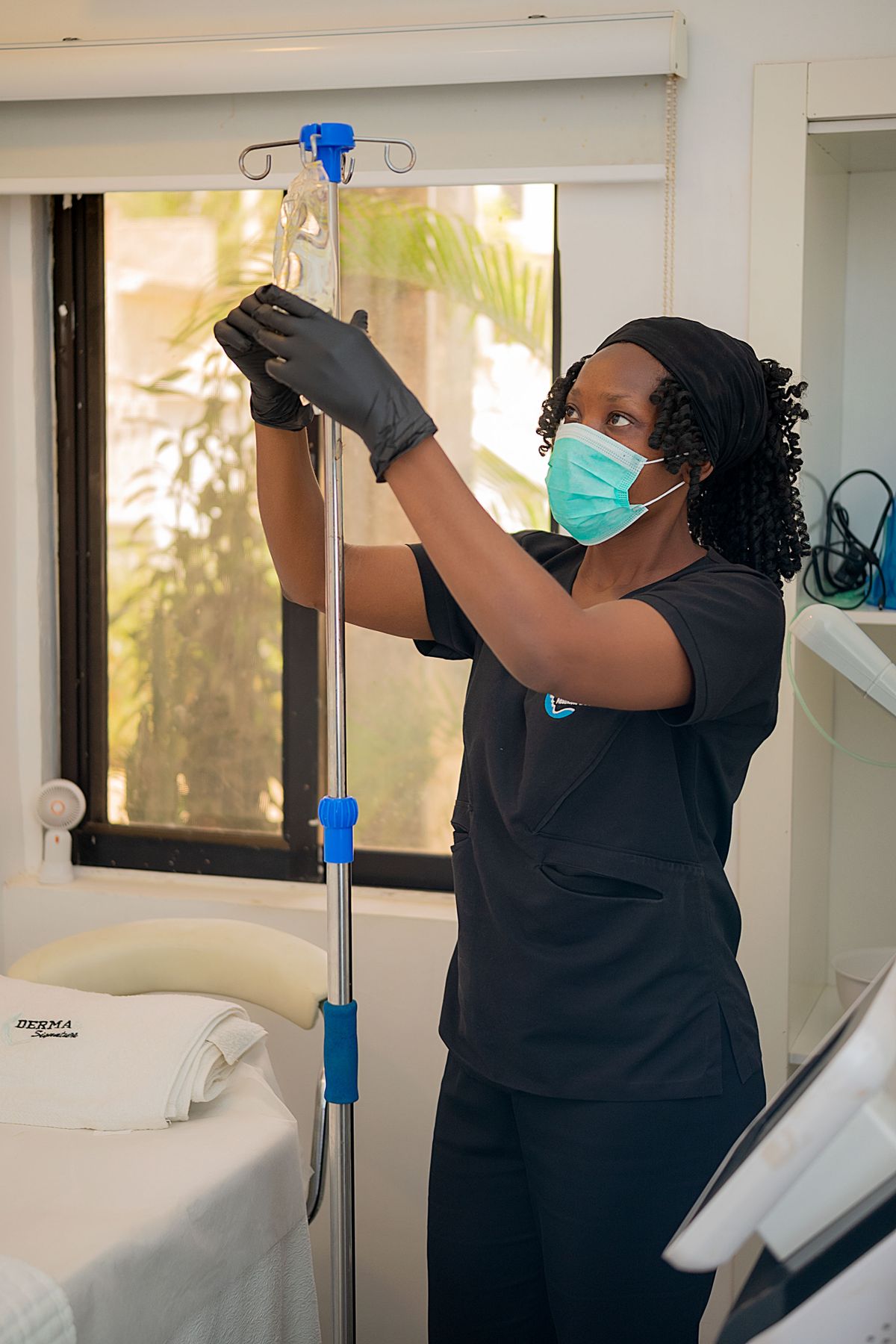 IV Therapy Clinic Professional Medical professional preparing an IV drip bag on a stand in a treatment room at D&M Treatments